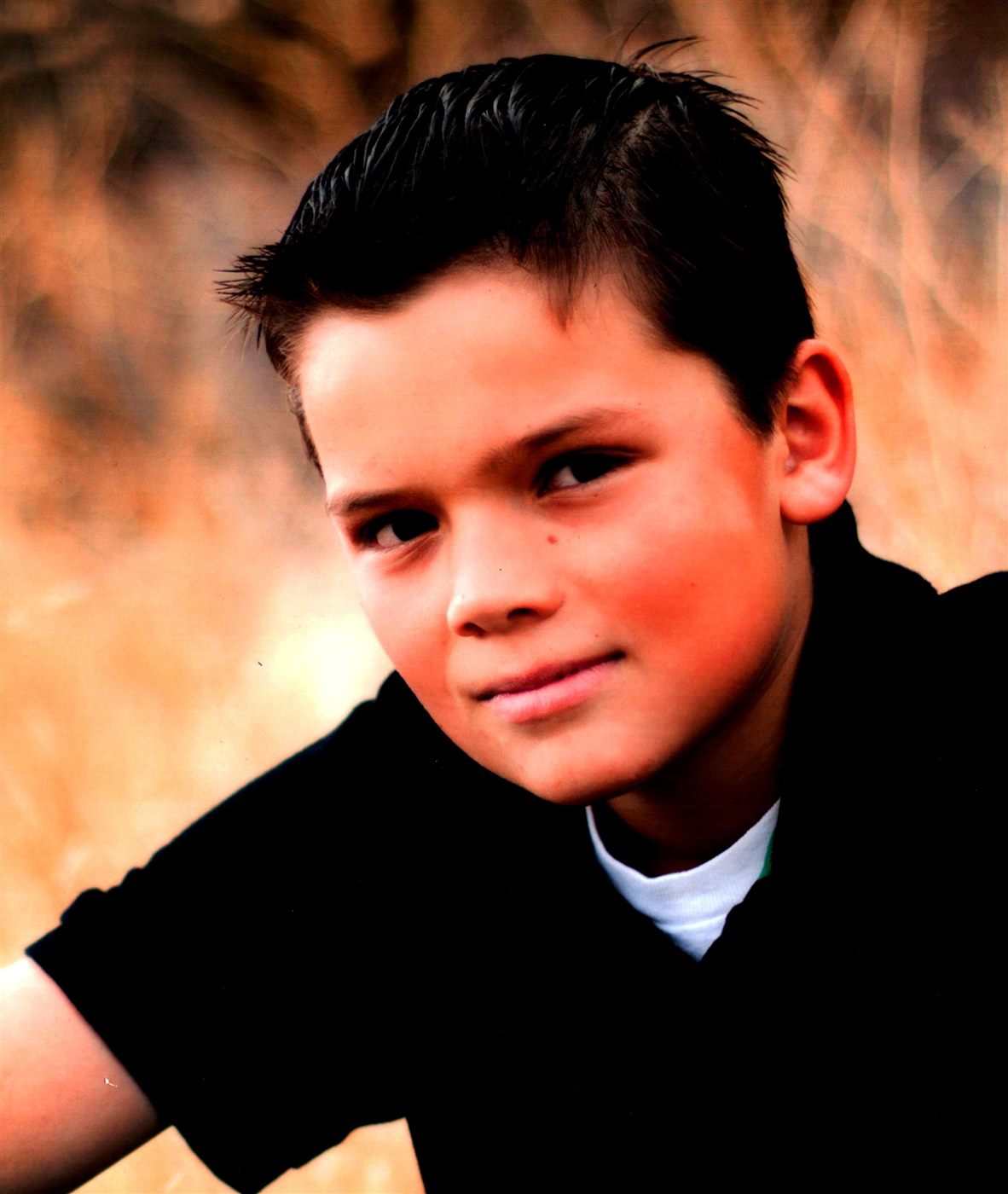 Studio portrait of young Caden in a black sweater with a gentle smile
