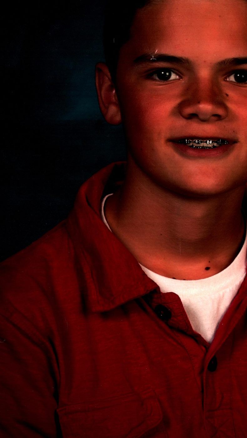 Teenage Caden smiling with braces in a rust-red shirt
