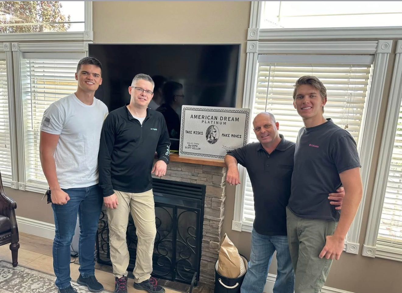 Caden with mentors beside an American Dream plaque reading Take Risks, Make Moves