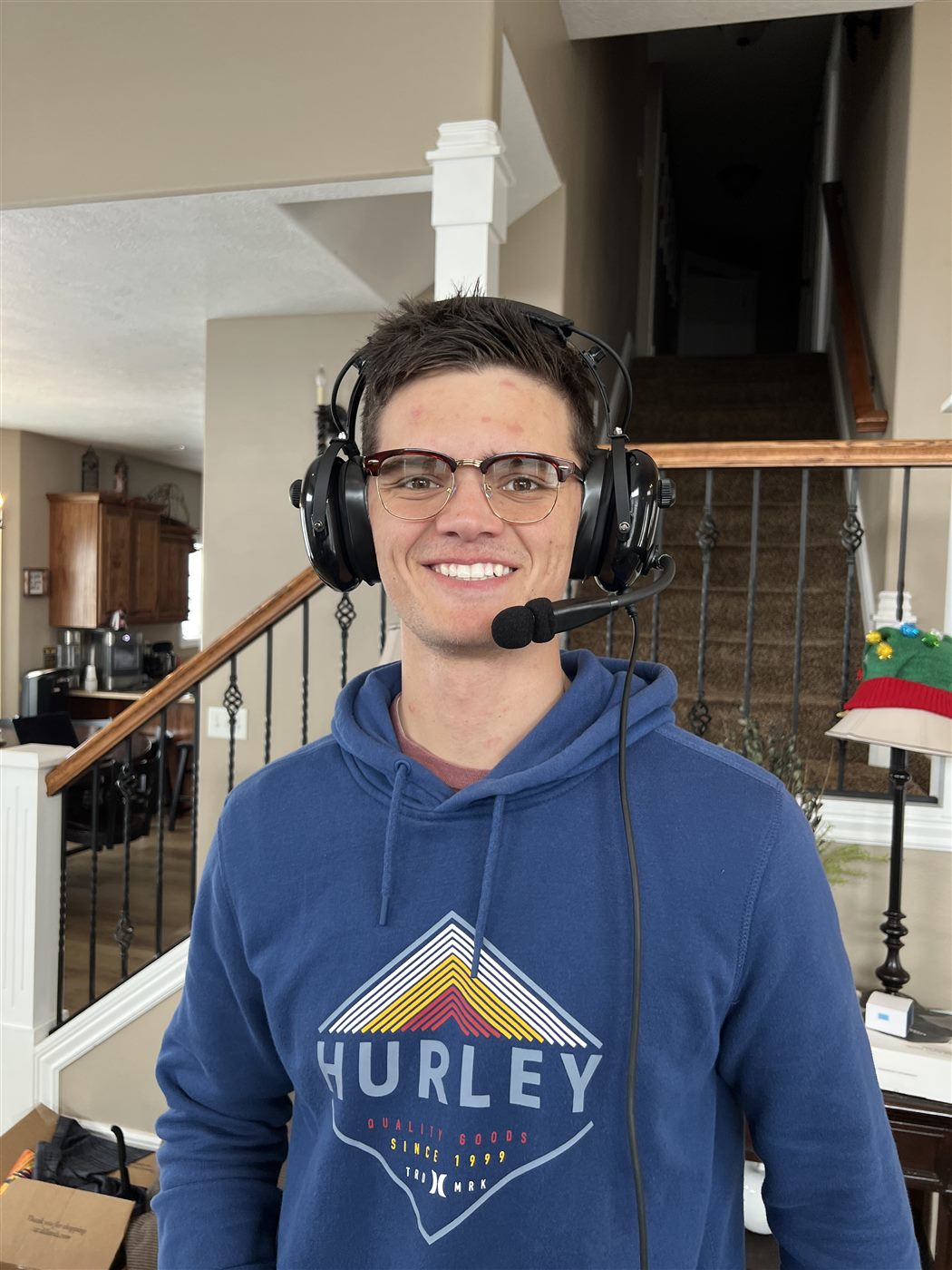 Caden at home wearing an aviation headset and smiling