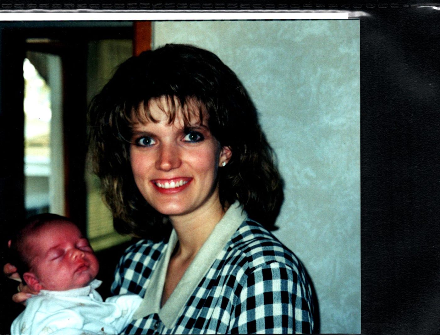 Young Maxine smiling while cradling her sleeping newborn