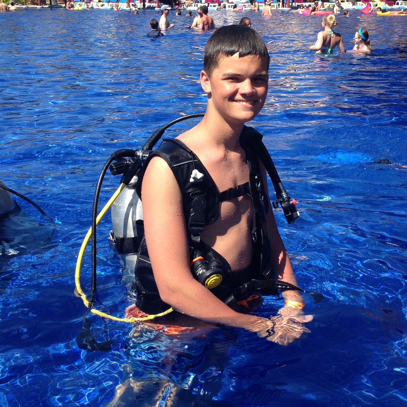 Caden in scuba gear giving a thumbs up in a bright blue pool