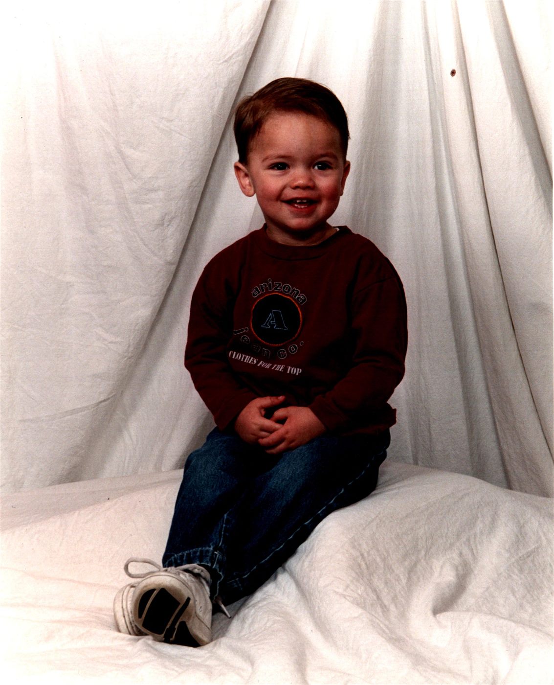 Toddler Caden grinning in a maroon sweatshirt