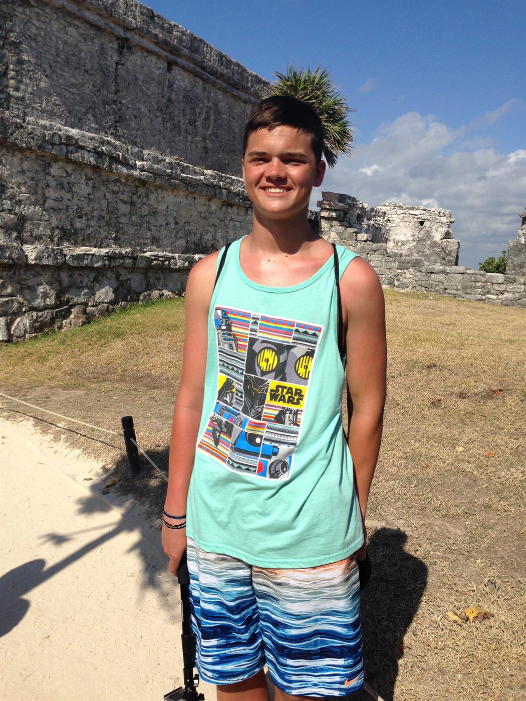 Caden smiling in front of Mayan ruins in a Star Wars tank top